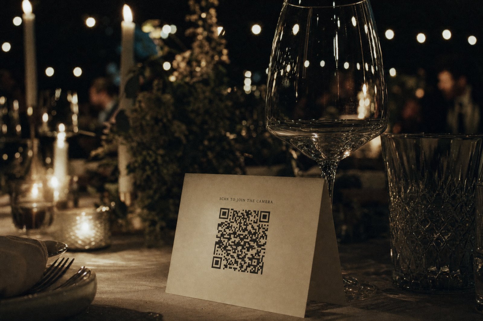 A blank place card leaning against a wine glass on a candlelit wedding reception table