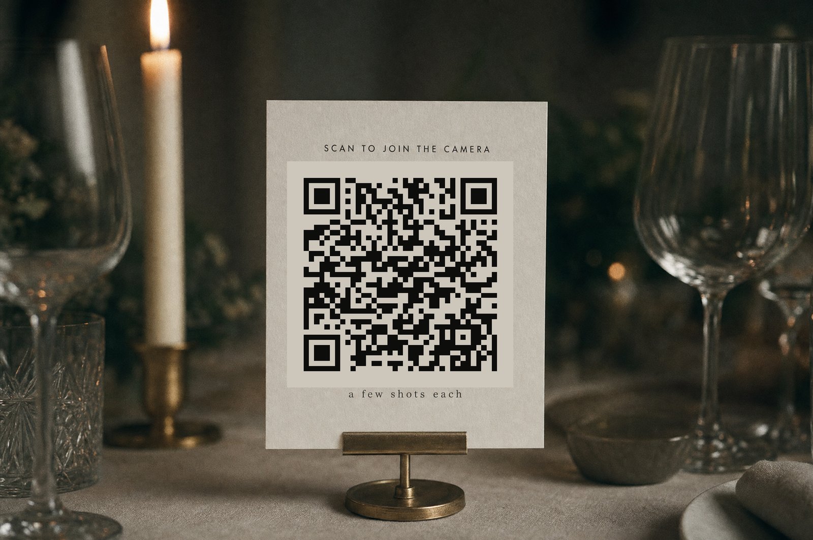 A blank card standing in a brass holder on a wedding table, the spot where the QR code goes